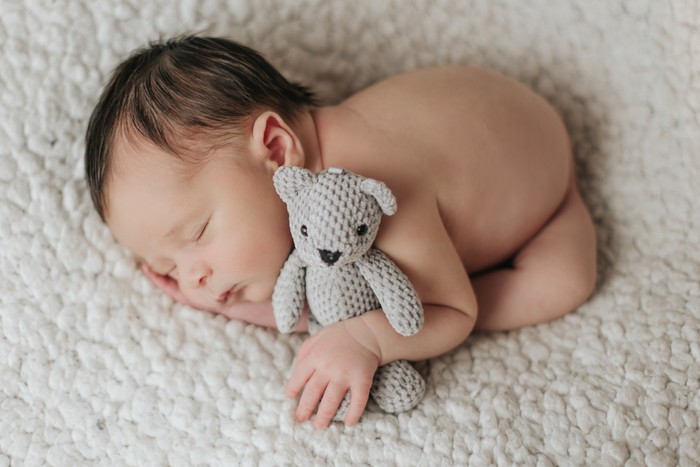 Sessão newborn, bebé recém-nascido em pose delicada com acessórios artesanais