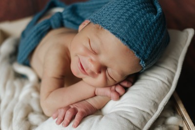 Fotografia newborn, bebé a dormir embrulhado em pano suave cor creme